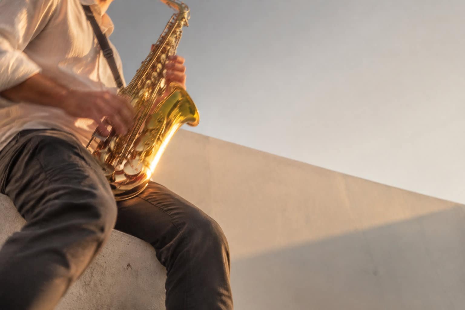 Improvisation jazz au saxophone Un saxophoniste jouant en plein air sous une lumière dorée de fin de journée.
