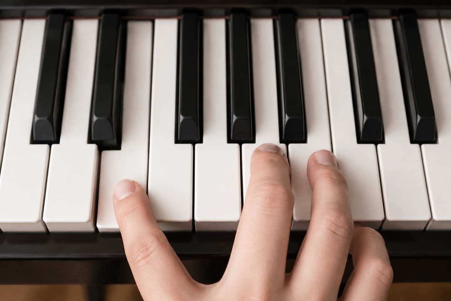 Une main joue sur les touches d’un piano.